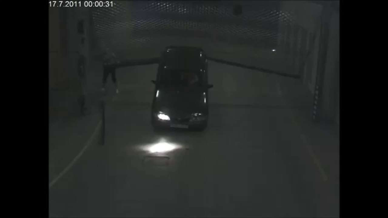 Une voiture passe sous la porte grillagée d'un parking souterrain