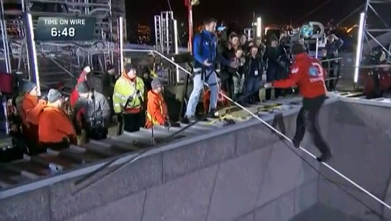 Un funambule marche les yeux bandés sur une corde entre deux buildings
