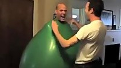 Guy climbs inside a giant green balloon
