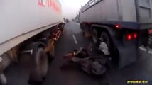 un homme veut passer avec son scooter entre deux camions !