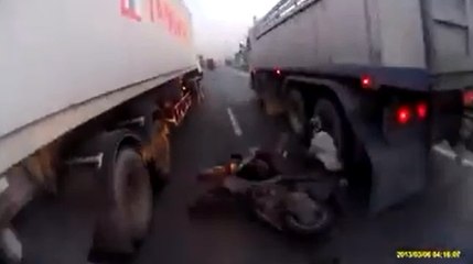 un homme veut passer avec son scooter entre deux camions !