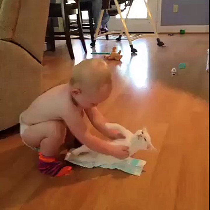 Ce bébé essaie de mettre une couche à son chat MDR !