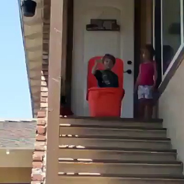 Un enfant dans une boite se fait pousser dans l'escalier par un copain