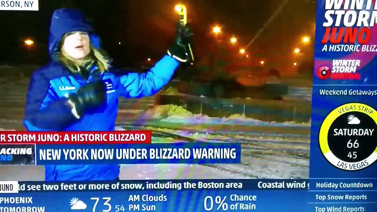 Il s'amuse avec son chasse neige derrière la présentatrice télé