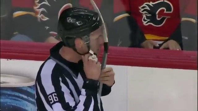 Un joueur de hockey coince sa crosse dans le casque de l'arbitre pendant un match