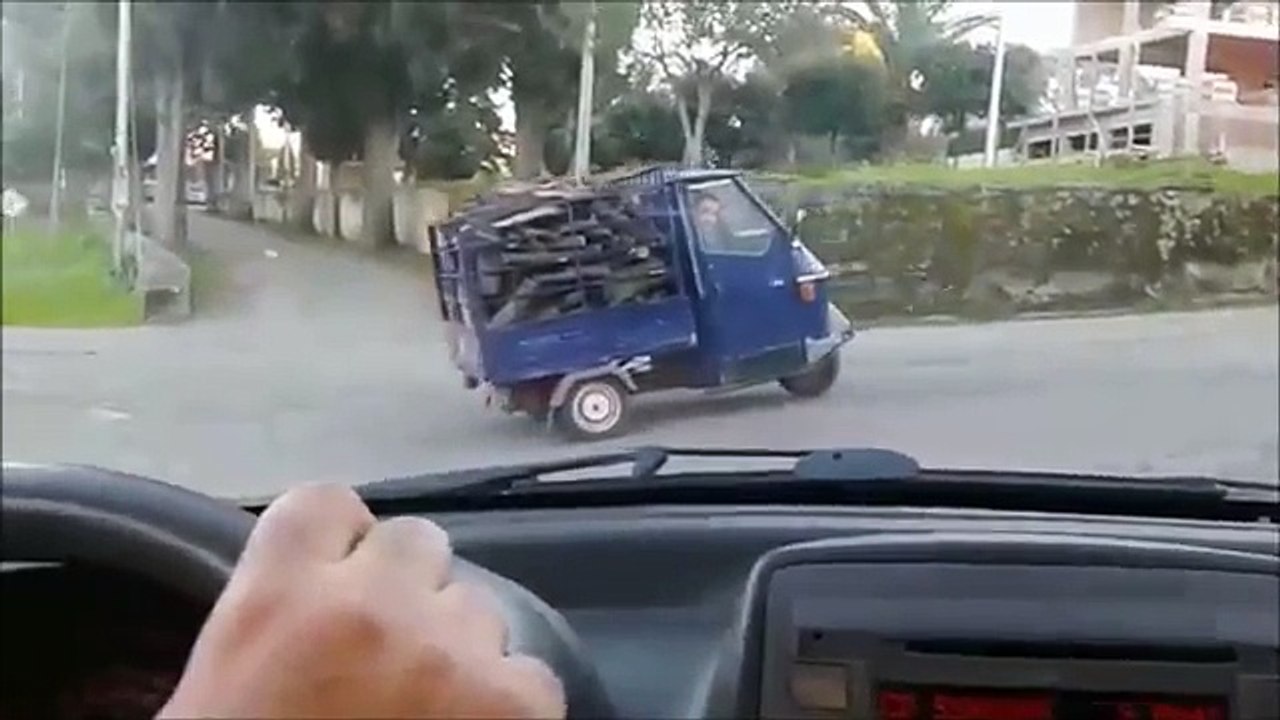 Un Piaggio Ape 50 essaie de grimper une pente avec un chargement de bois