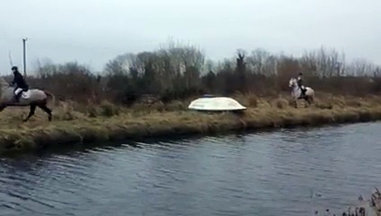 Des cavaliers sautent par dessus un bateau retournée sur la berge