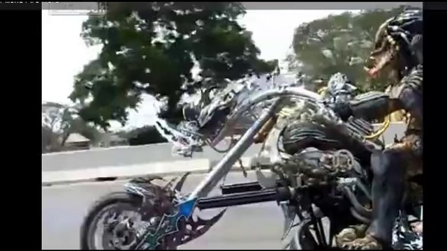 Guy dressed like the Predator cruising down the highway on his custom bike