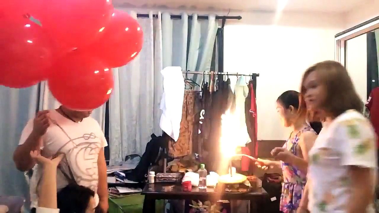 Des ballons gonflés à l'hélium explosent avec les bougies d'un gâteau d'anniversaire