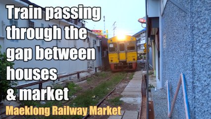 Train passing through the gap between houses & market