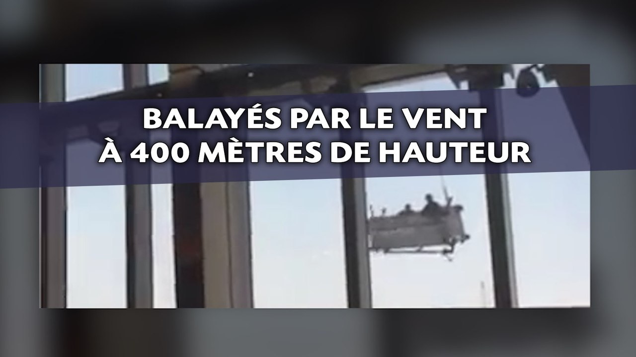 Deux laveurs de carreaux balayés par le vent en haut d'un gratte-ciel