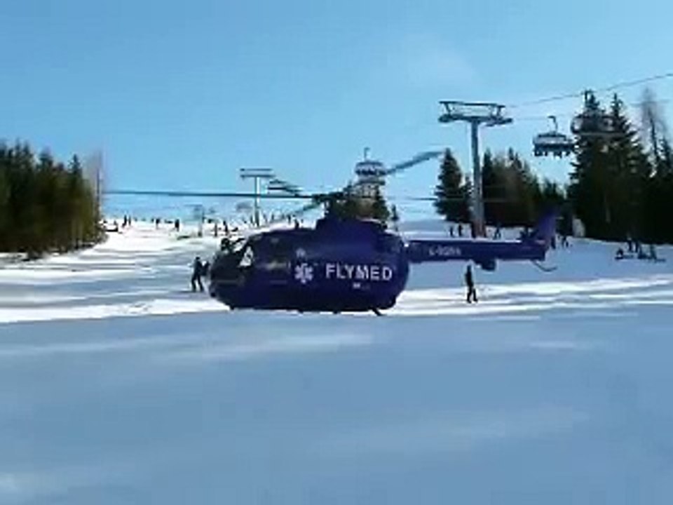 Rescue helicopter taking off from ski run
