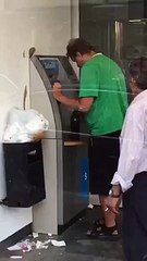 A drunk man withdraws money at a cash machine