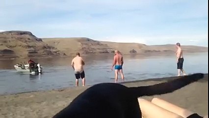 Un homme prend sa douche derrière un bateau à moteur. Et il n'a même pas lâché sa bouteille de bière !