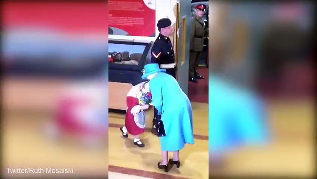Ouch! Little girl presents a posy to the Queen... only to be smacked on the head by a saluting soldier