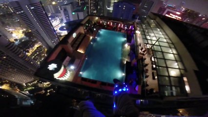 Guy parachutes from one building into a hotel roof pool