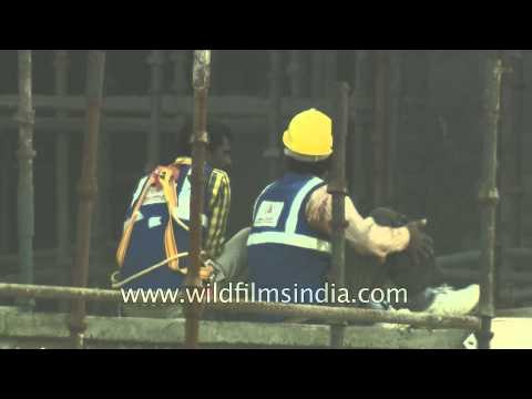 Construction workers perch precariously on in-construction building in India