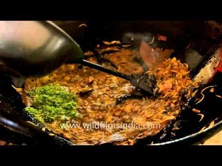 Woman makes fish curry at a Bengali wedding - India