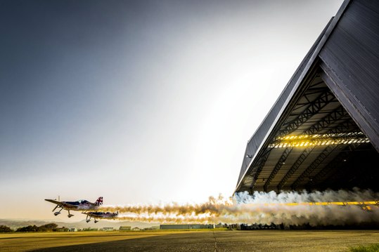Two Planes Fly Through a Hangar – Red Bull Barnstorming