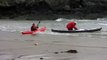A Sea Kayaker paddles into the surf at Porth Dafarch, Anglesey