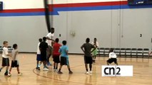 Un joueur de NBA dunk en sautant au dessus d'un gamin