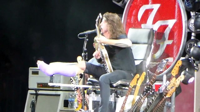 Dave Grohl des Foo Fighters assit sur un trone de guitares en live en mode Game Of Thrones