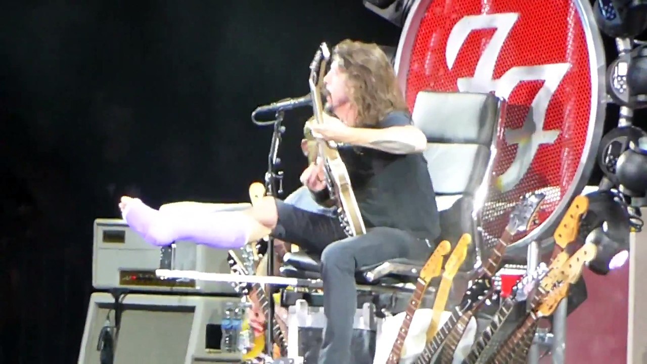 Dave Grohl des Foo Fighters assit sur un trone de guitares en live en mode Game Of Thrones
