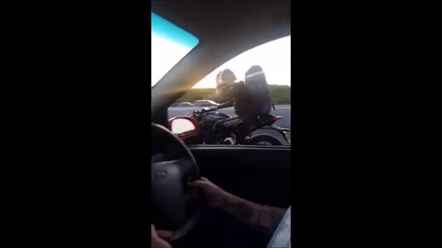 Un automobiliste et un motard jouent à Pierre, Feuille, Ciseau sur l'autoroute