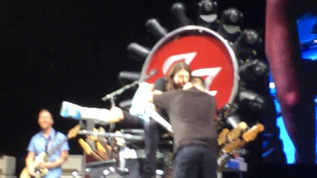 Dave Grohl laisse un fan jouer avec lui pendant un concert des foo fighters