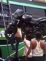 Indian Guy puts motorcycle on roof of a bus with his head