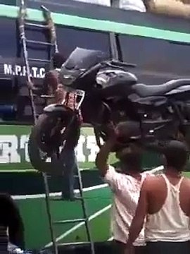 Индус поднимает мотоцикл головой на автобус