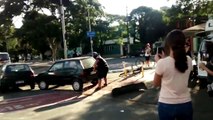 Un homme déplace une voiture garée sur une piste cyclable à mains nues