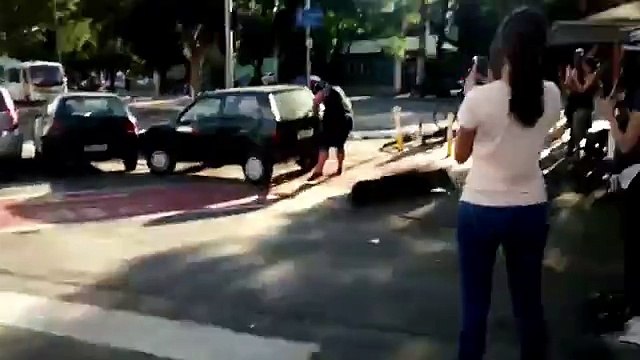 Un homme déplace à la force des bras une voiture qui bloque la route