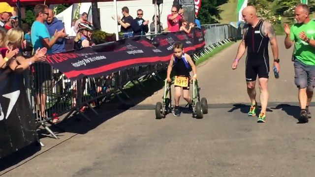 Criança com paralisia cerebral deixa o seu andarilho para cruzar meta de triatlo