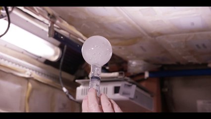 Un astronaute en apesanteur dissout un comprimé effervescent dans une bulle d’eau