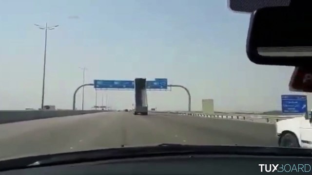 La benne de ce camion n'est pas baissée et va heurter un panneau de signalisation