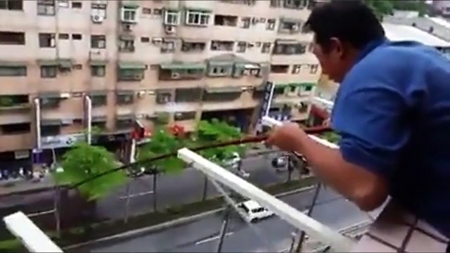 Un homme pêche depuis son balcon au 5eme étage d'un batiment