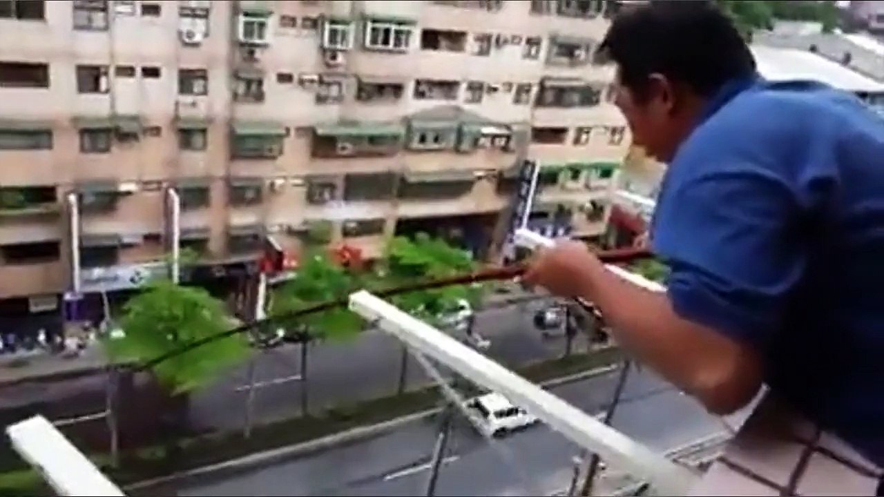 Un homme pêche depuis son balcon au 5eme étage d'un batiment