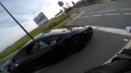 Motorcycle driver has fun and races with a Lamborghini