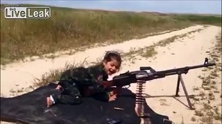 A little Arab girl has a go with a belt fed machine-gun
