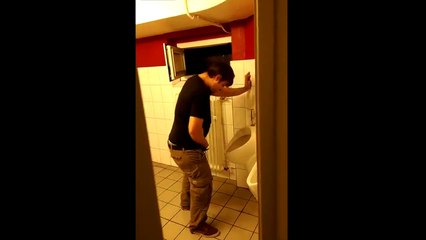 Un homme ivre essaie de se rhabiller aux toilettes