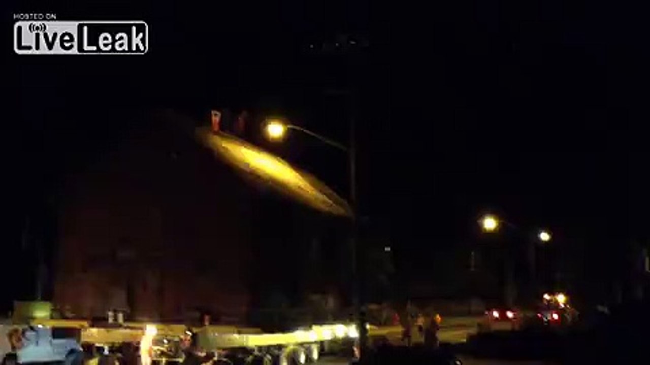 Old school house being towed down the street.