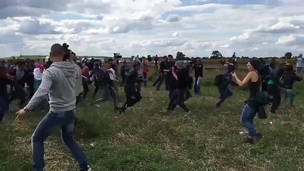 Une caméraman fait un croche-pied à un migrant