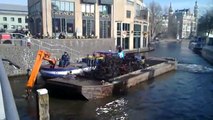Boat crane cleaning water in Amsterdam channels from bikes