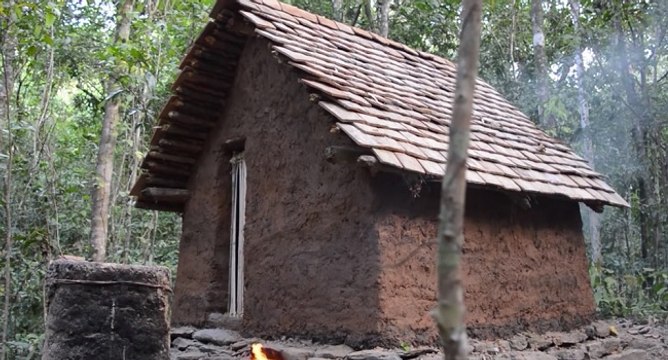 Un homme construit une cabane avec un toit en tuile