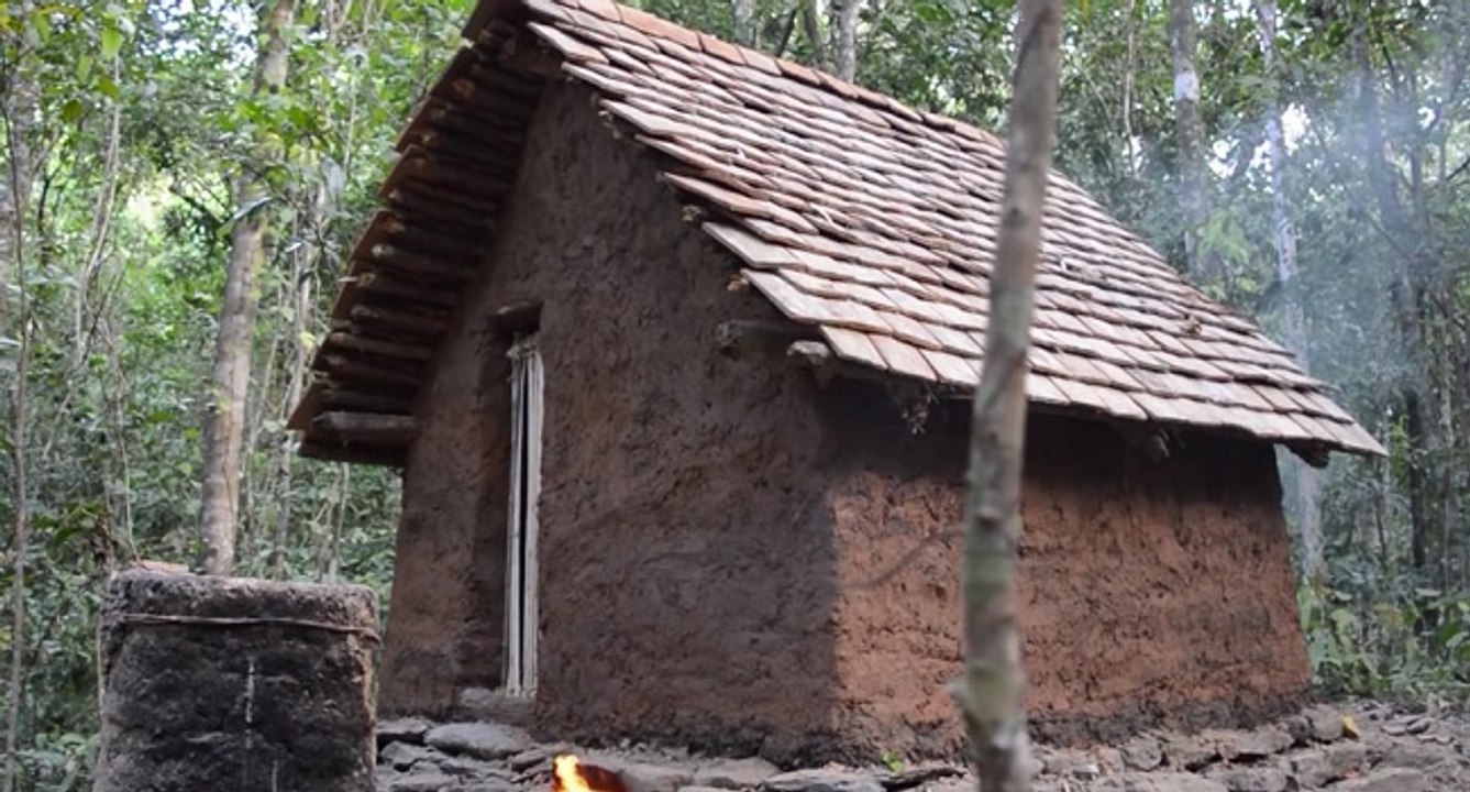 Un homme construit une cabane avec un toit en tuile