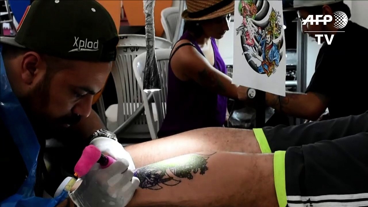 Körperkünstler zieht sich auf Tattoo-Messe an Haken hoch