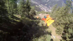 Trois wingsuiters volent à travers les arbres d'une montagne