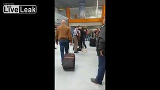 Guy  waiting for his girlfriend at  the airport with a guitar and flowers