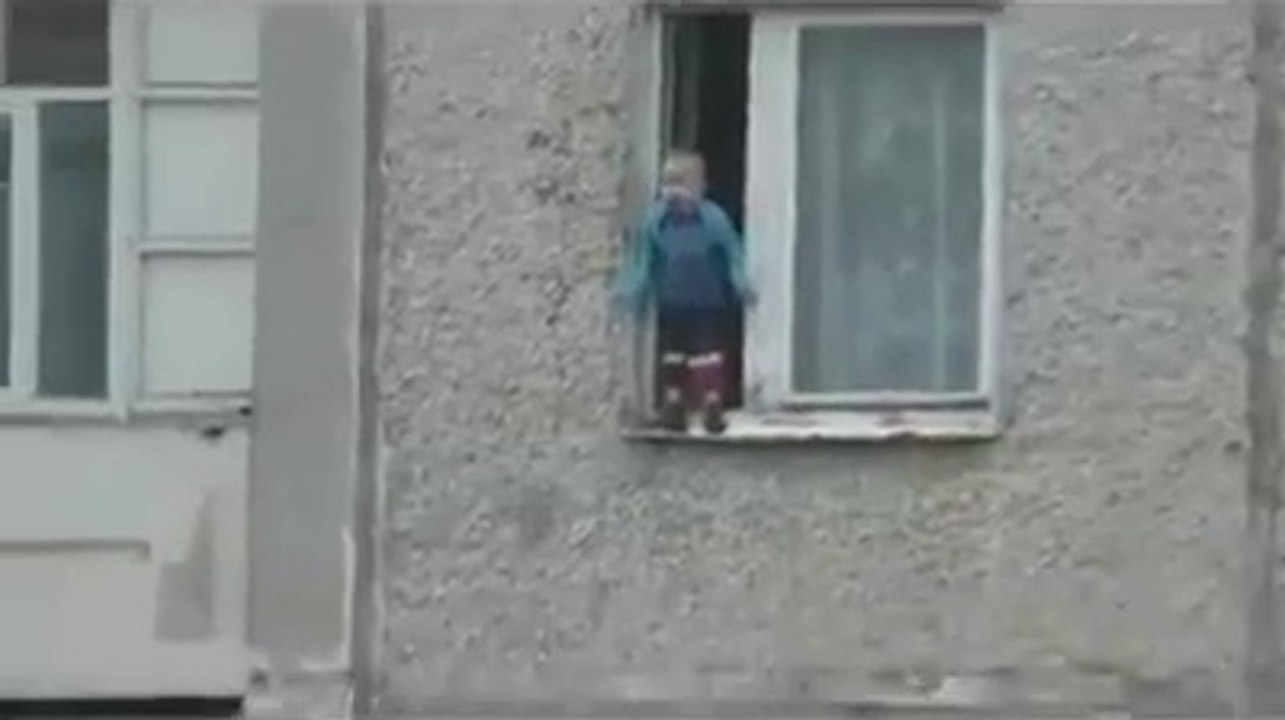 Un enfant russe joue sur le bord d'une fenêtre au 8ème étage